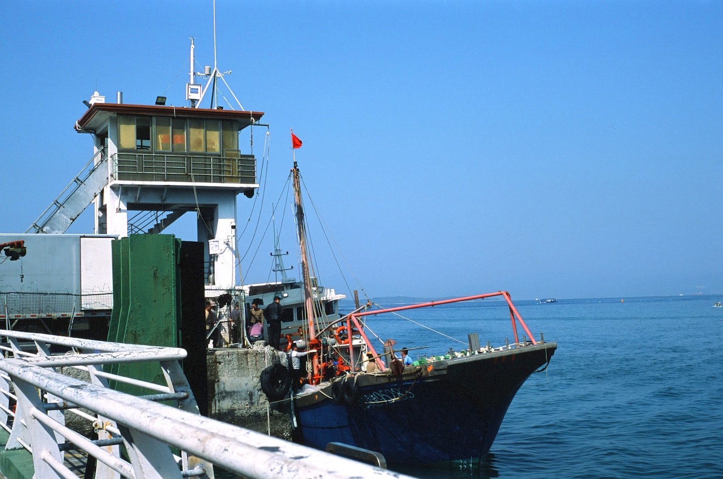 A working passenger vessel alongside a pier under a clear blue sky